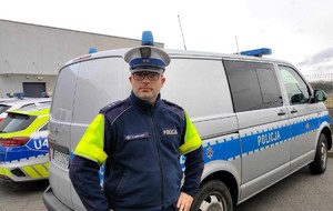 Policjant stoi przy radiowozie policyjnym