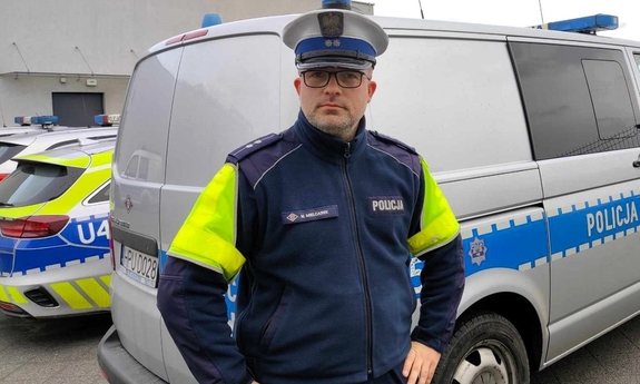 Policjant stoi przy radiozie.