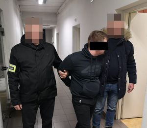 mężczyzna prowadzony przez dwóh policjantów