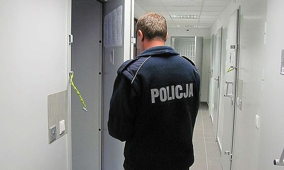 Umundurowany policjant zamyka drzwi policyjnej celi.