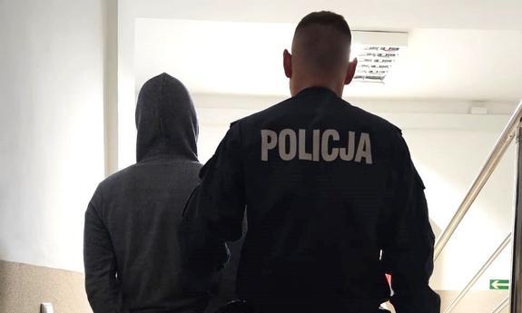 Policjant prowadzi zatrzymanego mężczyznę.