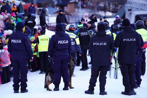 Na zdjęciu umundurowani policjanci z psem na stoku narciarskim.