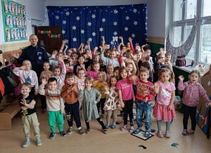 Policjant pozuje do zdjęcia z grupą dzieci.