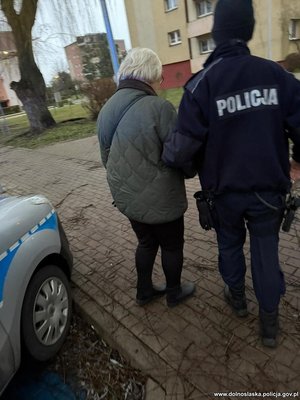 Policjant idzie ze starszą kobietą.