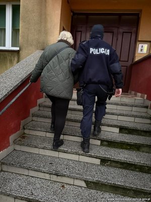 Policjant idzie ze starszą kobietą.