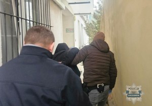 Policjanci prowadza zatrzymanego mężczyznę.