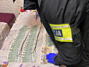 Funkcjonariusz rozkłada na stole banknoty pieniędzy.