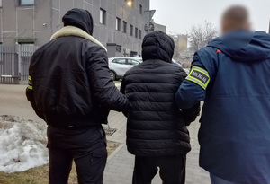 Dwaj nieumundurowani policjanci prowadzą zatrzymanego.