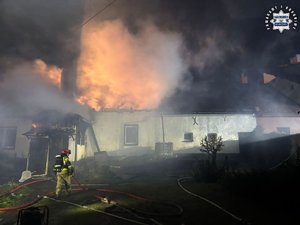 Strażacy gaszą płonący budynek.