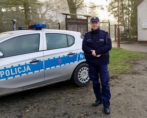 Policjant stoi przy radiowozie.