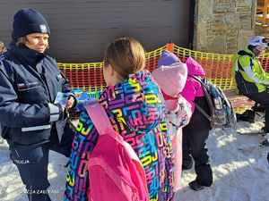 Policjantka rozdaję ulotki promujące bezpieczne zachowania.