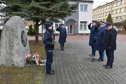 Delegacja policjantów składa kwiaty i oddaje honory przed pomnikiem.