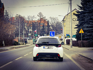 Samochód nauki jazdy na ulicy miasta - zdjęcie poglądowe.