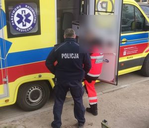 Policjant i ratownik medyczny przy karetce.