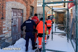 Policjant i ratownicy pomagają kobiecie.