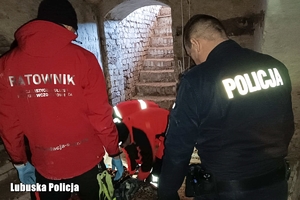 Policjant i ratownicy pomagają kobiecie.