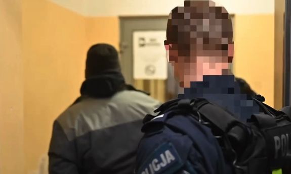 z przodu stoi policjant, za nim zatrzymany.