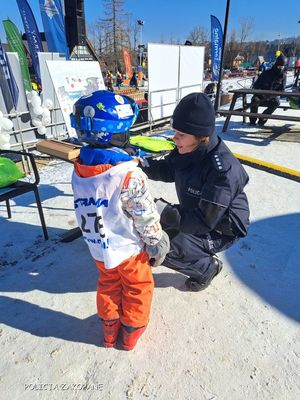 Policjantka z dzieckiem przy stoisku profilaktycznym.