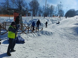 Policjant mierzy prędkość zjeżdżających po stoku narciarzy.