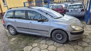 Zabezpieczony pojazd marki Peugeot na parkingu. W tle brama i zaparkowane inne pojazdy.