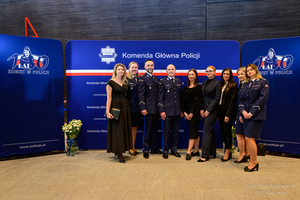 Obrazek pokazuje delegację z Biura Logistyki Policji Komendy Głównej Policji na specjalnym koncercie w sali NOSPR w Katowicach. Koncert odbył się z okazji Międzynarodowego Dnia Kobiet, upamiętniając 100. rocznicę powstania Policji Kobiecej w Polsce pod hasłem „Policja jest Kobietą”.