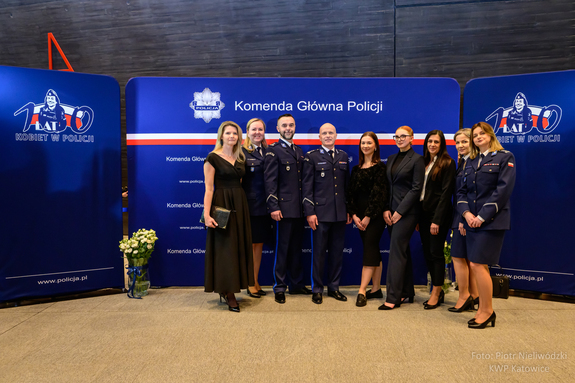 Obrazek pokazuje delegację z Biura Logistyki Policji Komendy Głównej Policji na specjalnym koncercie w sali NOSPR w Katowicach. Koncert odbył się z okazji Międzynarodowego Dnia Kobiet, upamiętniając 100. rocznicę powstania Policji Kobiecej w Polsce pod hasłem „Policja jest Kobietą”.