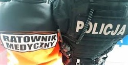 Plecy stojących obok siebie funkcjonariuszy publicznych. Jeden to ratownik medyczny, drugi to policjant.