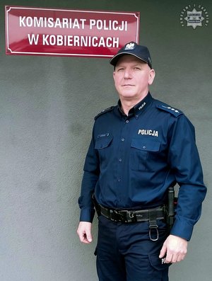 policjant stoi przed budynkiem policji.