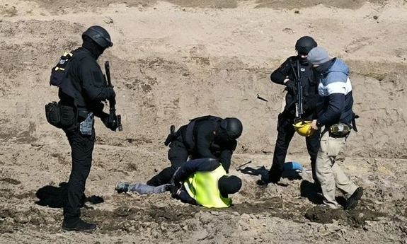 trzech policjantów zatrzymuje mężczyznę.
