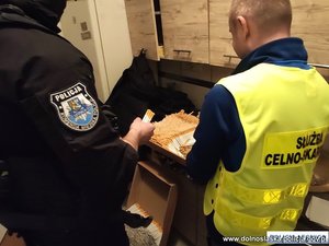 Policjant i funkcjonariusz służby celnej przy maszynce z papierosami.