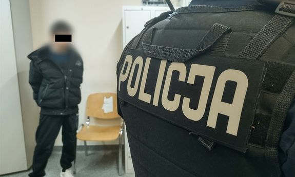 plecy policjanta. przed nim stoi zatrzymany.