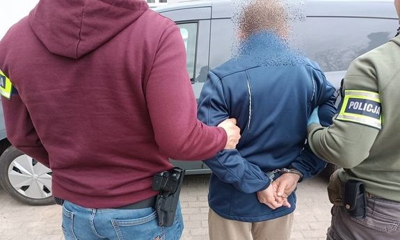 Dwaj nieumundurowani policjanci prowadzą zatrzymanego mężczyznę. Widok z tyłu.
