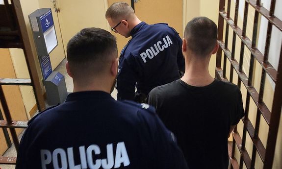 Dwaj policjanci prowadzą zatrzymanego.