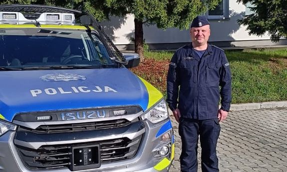 Umundurowany policjant przy radiowozie.