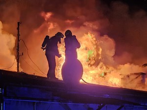 Strażacy na dachu palącego się budynku.
