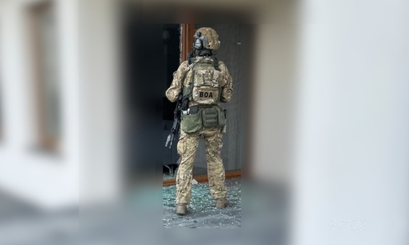 Policjant BOA przed drzwiami tarasowymi budynku.