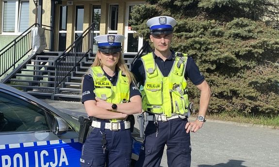 dwoje policjantów stoi przy radiowozie.