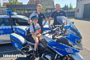 Policjanci wraz z chłopcem na motocyklu.