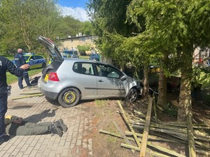 Samochód sprawców włamania. Jeden z zatrzymanych leży w kajdankach na ziemi. Obok policjanci.