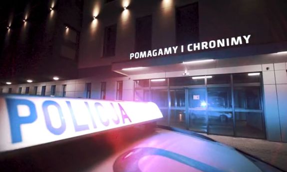 Sygnalizator świetlny na radiowozie z napisem Policja, w tle budynek komendy Policji.