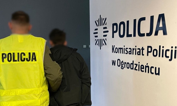 Nieumundurowany policjant w kamizelce odblaskowej z napisem Policja oraz zatrzymany mężczyzna.
