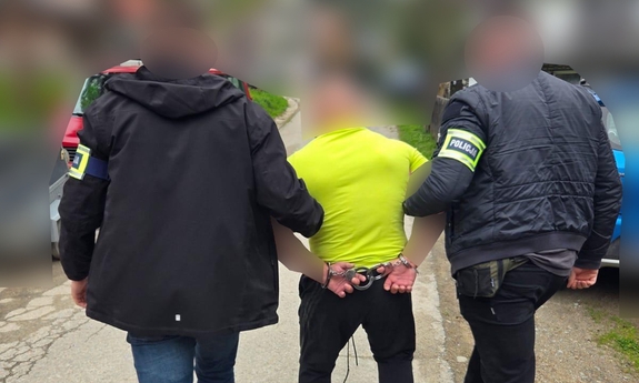 Na zdjęciu dwóch policjantów prowadzi zatrzymanego mężczyznę.