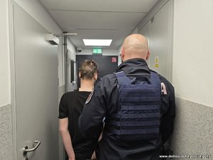 Na zdjęciu policjant prowadzi zatrzymanego mężczyznę.