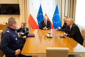 Na zdjęciu dwaj umundurowani policjanci, dwaj mężczyźni w strojach cywilnych i chłopiec
