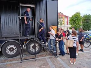 Policjanci i zwiedzający wchodzący po schodach do Escapetrucka.