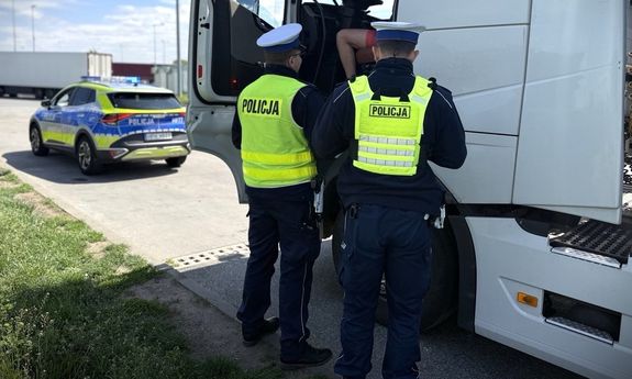 Dwaj policjanci kontrolują kierującego ciężarówką.