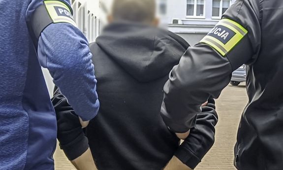 Dwaj nieumundurowani policjanci prowadzą zatrzymanego. Widok z tyłu.