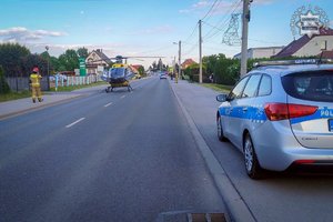Miejsce wypadku drogowego. Na drodze stoi śmigłowiec pogotowia ratunkowego, obok radiowóz.