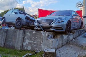 Miejsce wypadku drogowego. Uszkodzony samochód sprawcy wypadku i stojący obok inny samochód osobowy.