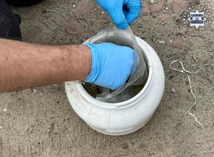 Dłonie w rękawiczkach i widoczny woreczek w plastikowym pojemniku.